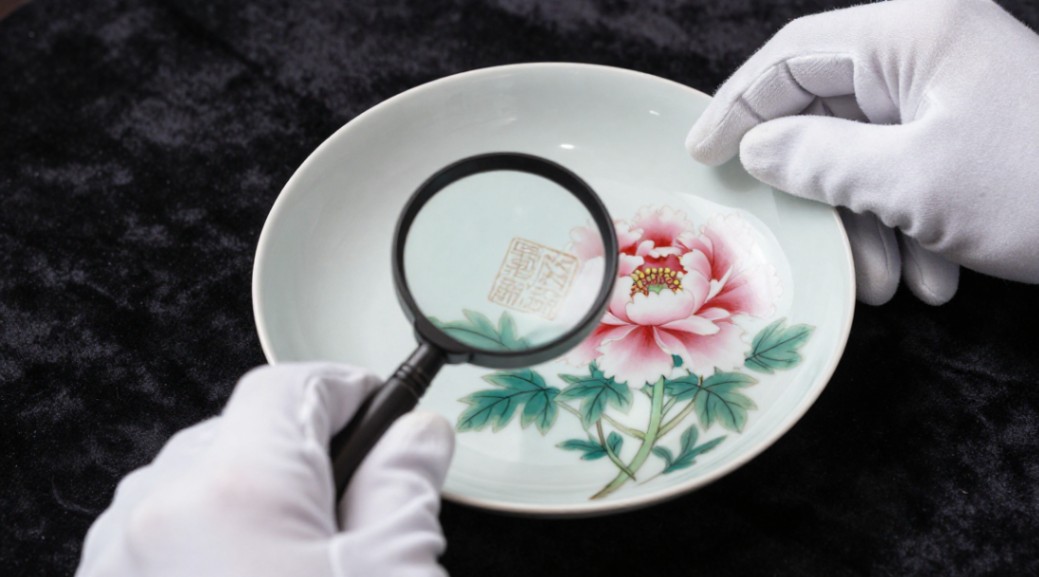 A collector inspects the artist's mark and brushwork to verify a piece's authenticity.